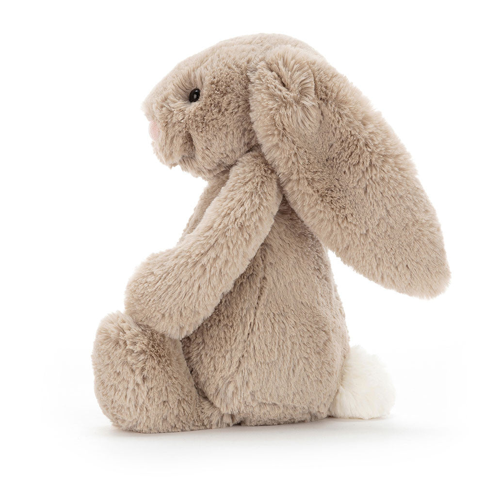 Side view of a Bashful Beige Bunny plush toy with long floppy ears and a white fluffy tail.