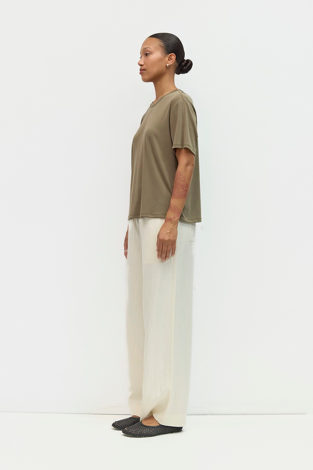 Side view of a person wearing cream-colored wide-leg Jodi Pants with a loose fit.