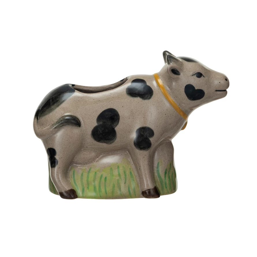 Stoneware cow vase with a crackle glaze, black spots, and a green grass base.