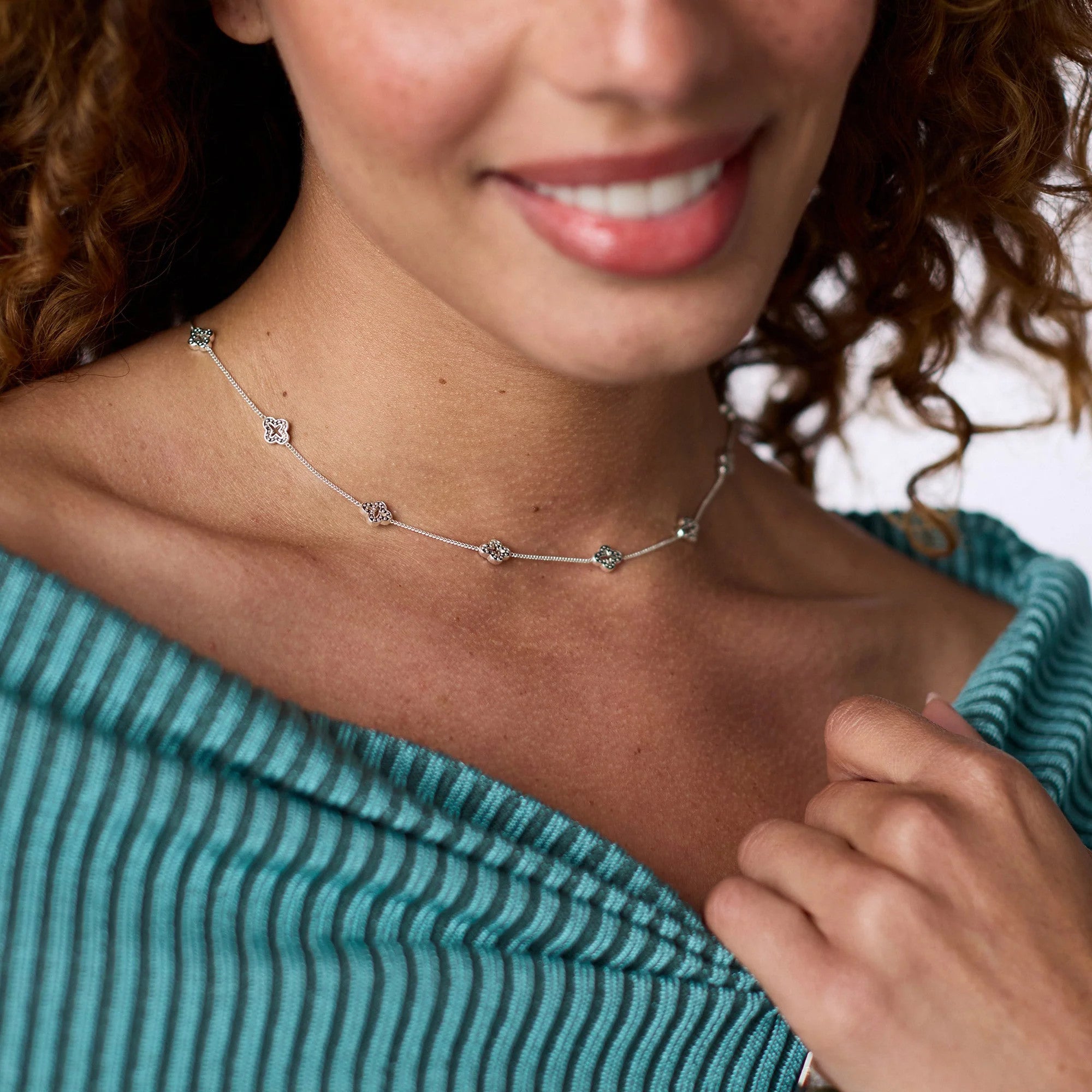 A woman wearing the Florentine Demi Delicate Station Necklace in silver with floral charms.