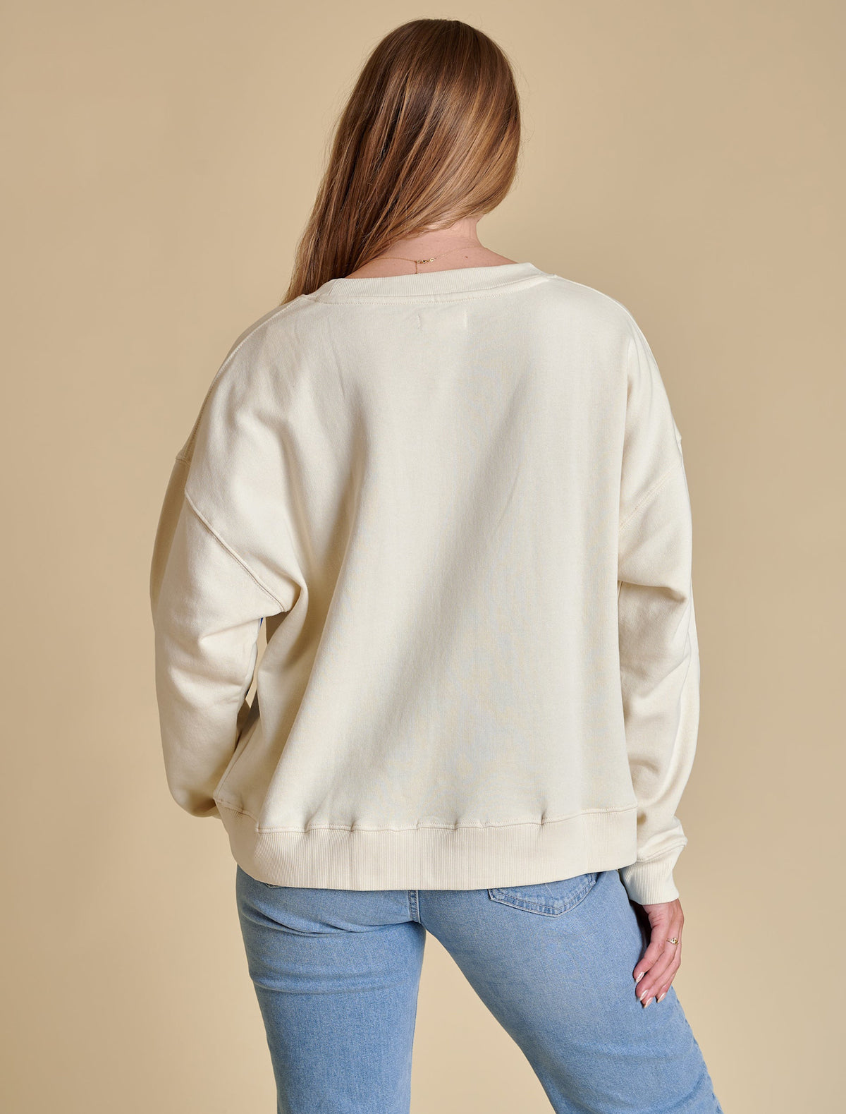 Back view of a beige boxy crewneck sweatshirt with long sleeves.