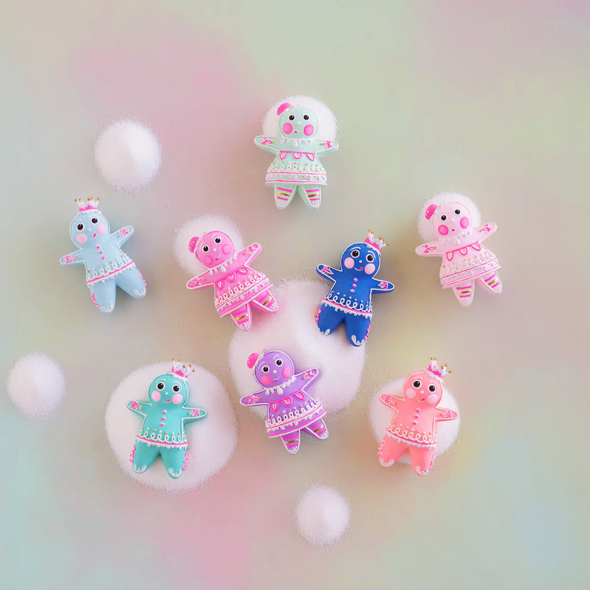 Hand-painted resin ornament featuring colorful whimsical gingerbread figures with sparkling details on a tree branch.