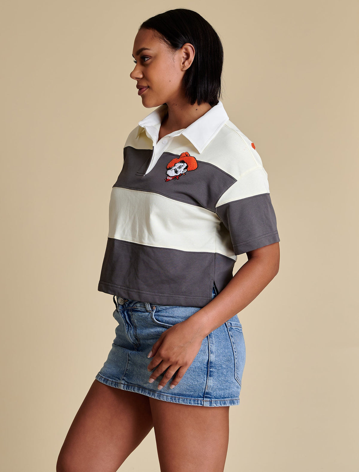 Side view of a boxy short sleeve rugby top with chenille embroidery placket and side slits in beige.
