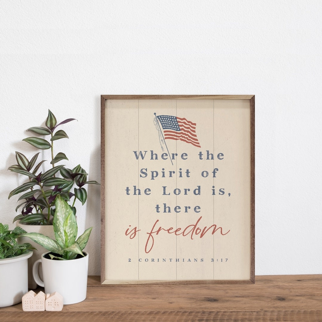 White framed wood wall art featuring the text 'There Is Freedom' with a natural walnut frame.