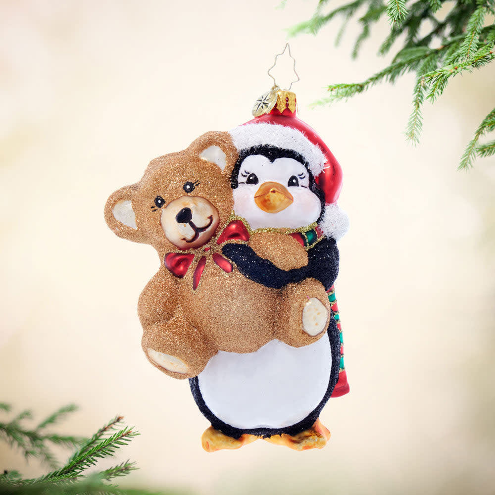 Penguin plush toy holding a small brown teddy bear.