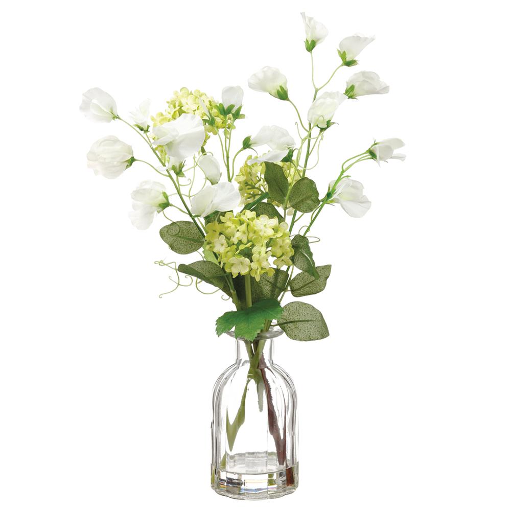 Glass vase with green sweet pea and white snowball flowers in a clear glass container.