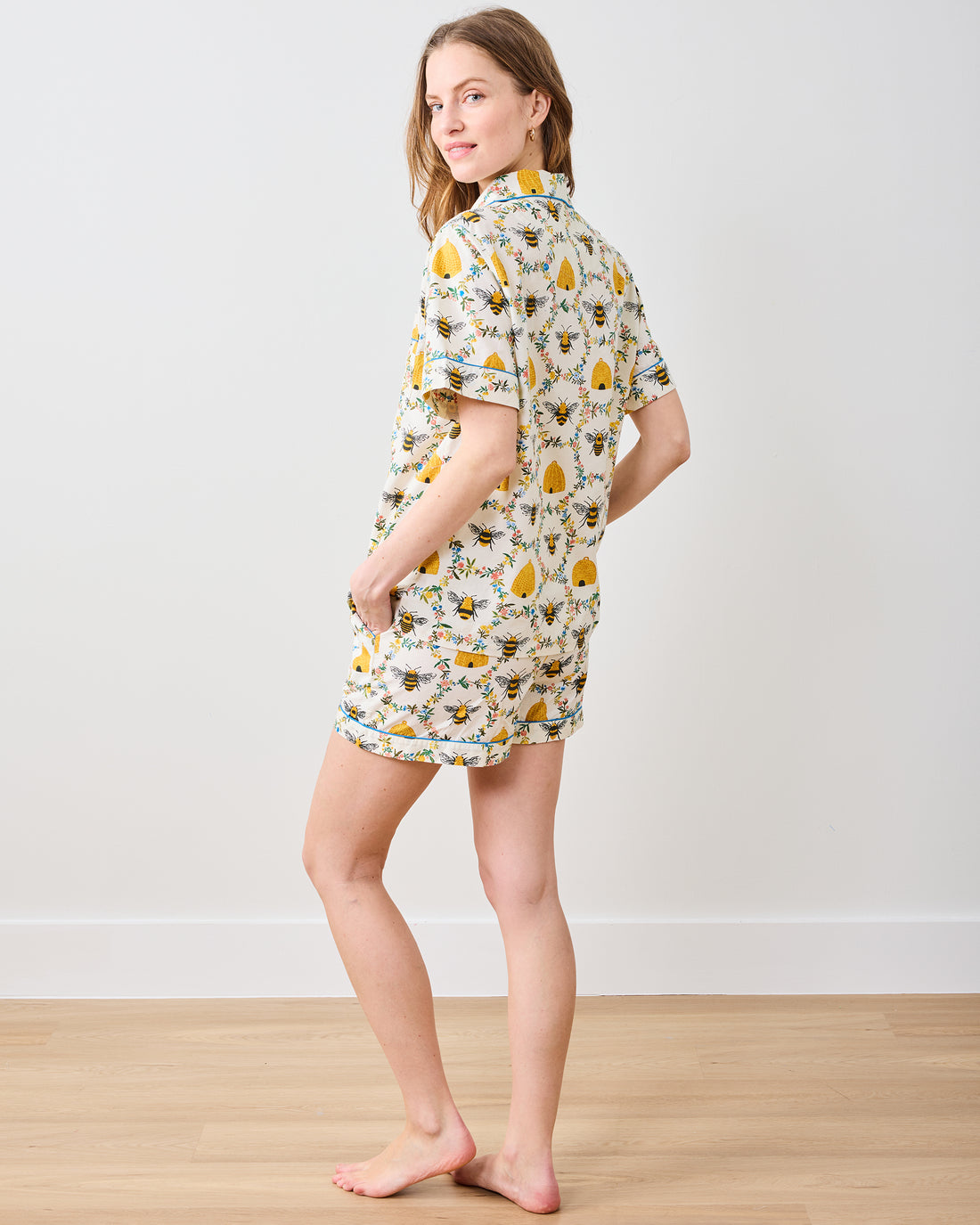 Woman wearing a white short-sleeved pajama set with a yellow bee and floral print.