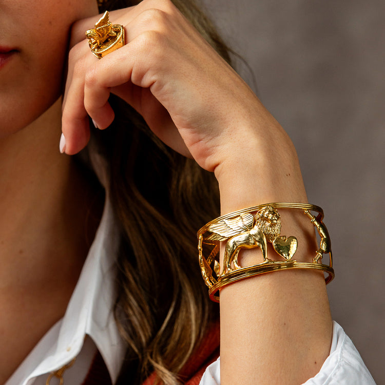 A woman wearing a gold Lionheart Cuff featuring a winged lion and heart on an open multi-band frame.