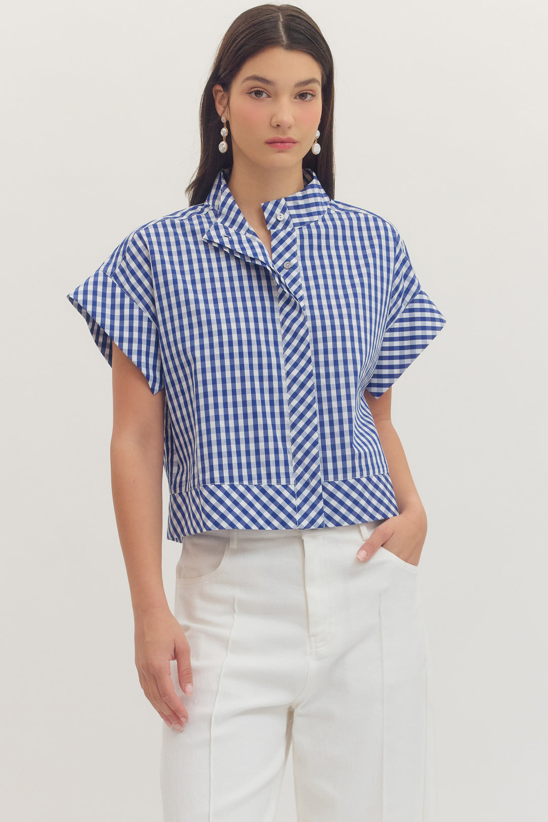 Woman wearing a blue and white Noemi Gingham Print Cap Sleeve Top with white pants.