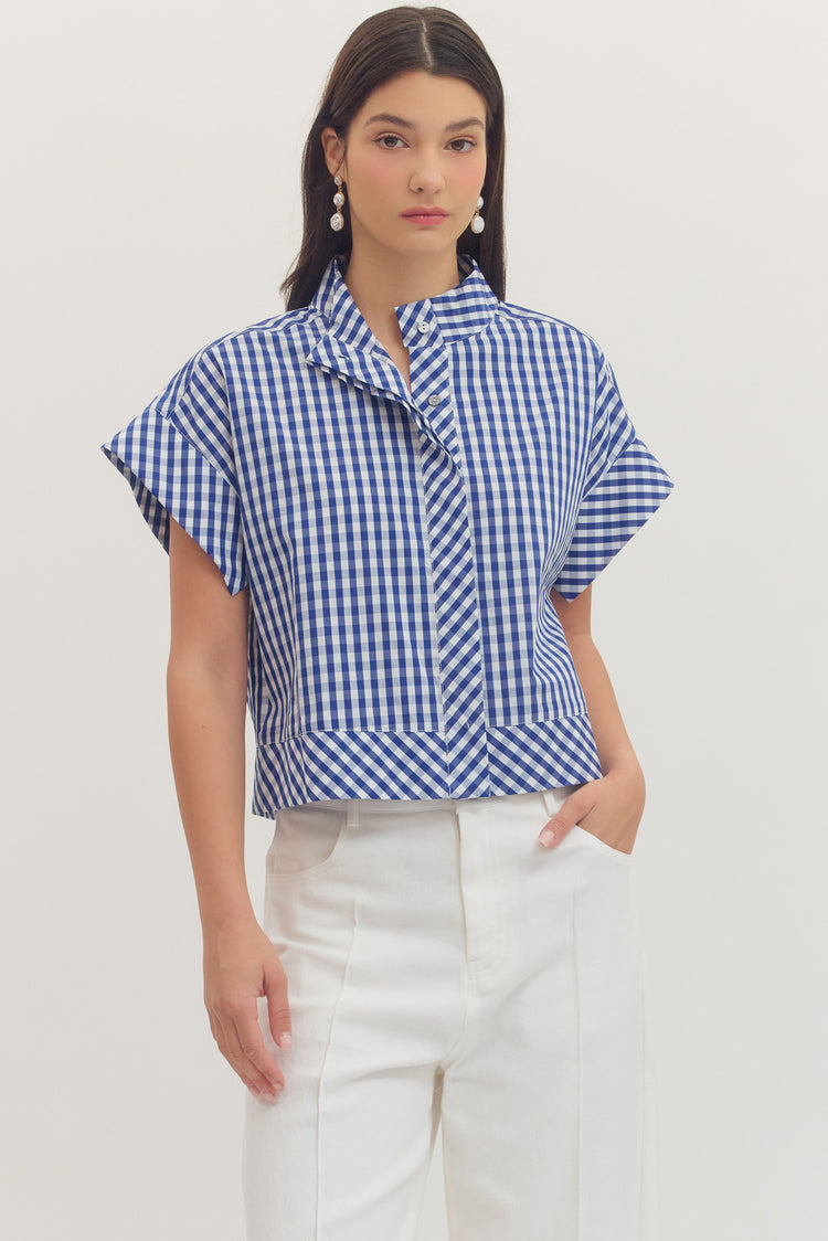 Woman wearing a blue and white Noemi Gingham Print Cap Sleeve Top with white pants.