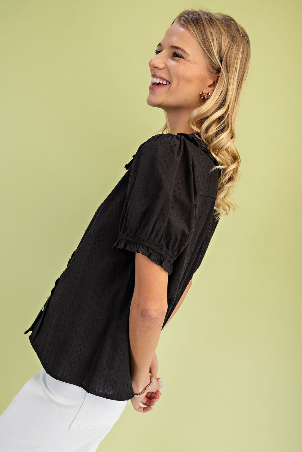 Side view of a woman wearing a black short puff sleeve blouse with a Peter Pan collar.