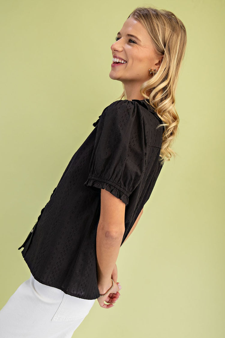 Side view of a woman wearing a black short puff sleeve blouse with a Peter Pan collar.