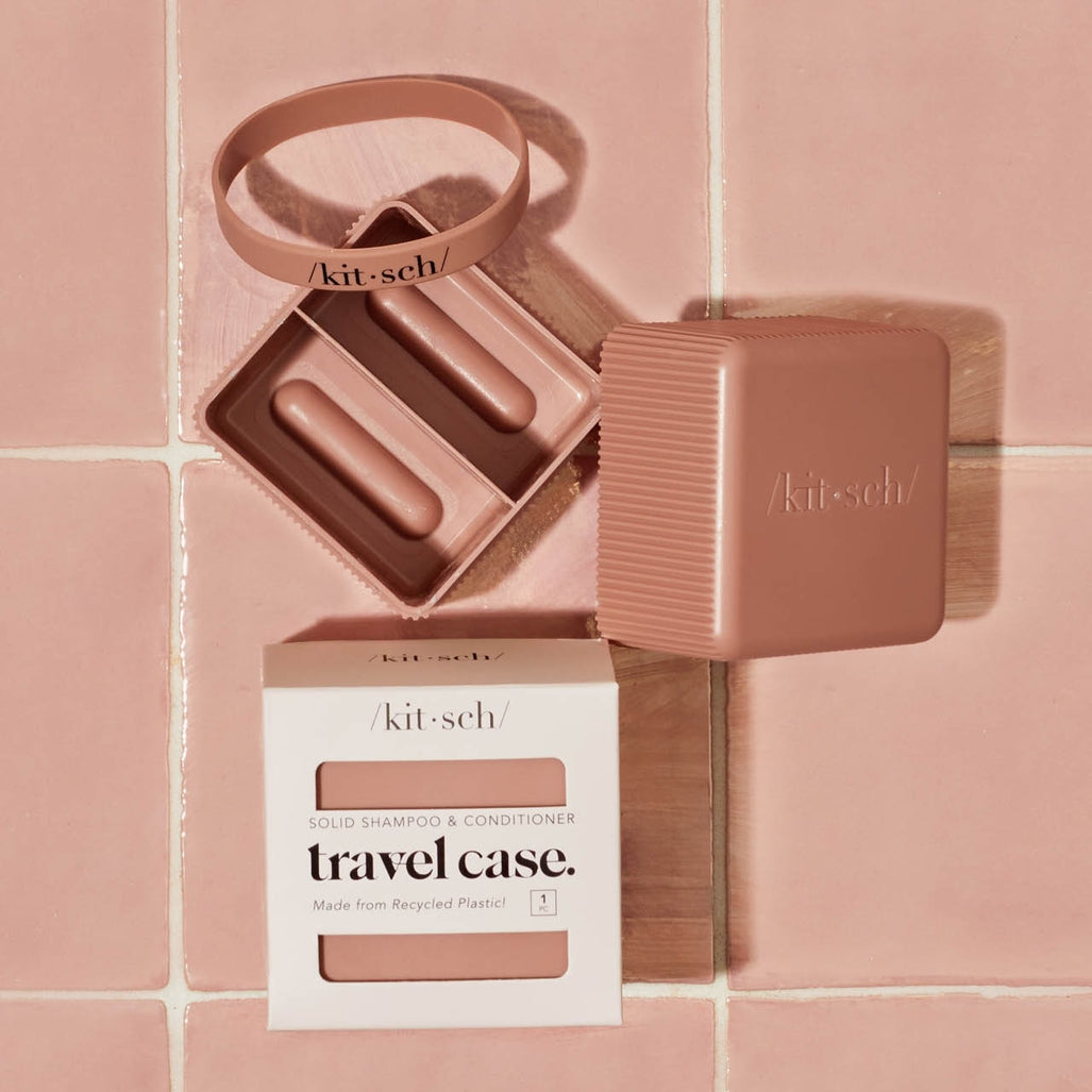Kitsch terracotta travel case for solid shampoo and conditioner bars on a pink tiled background.