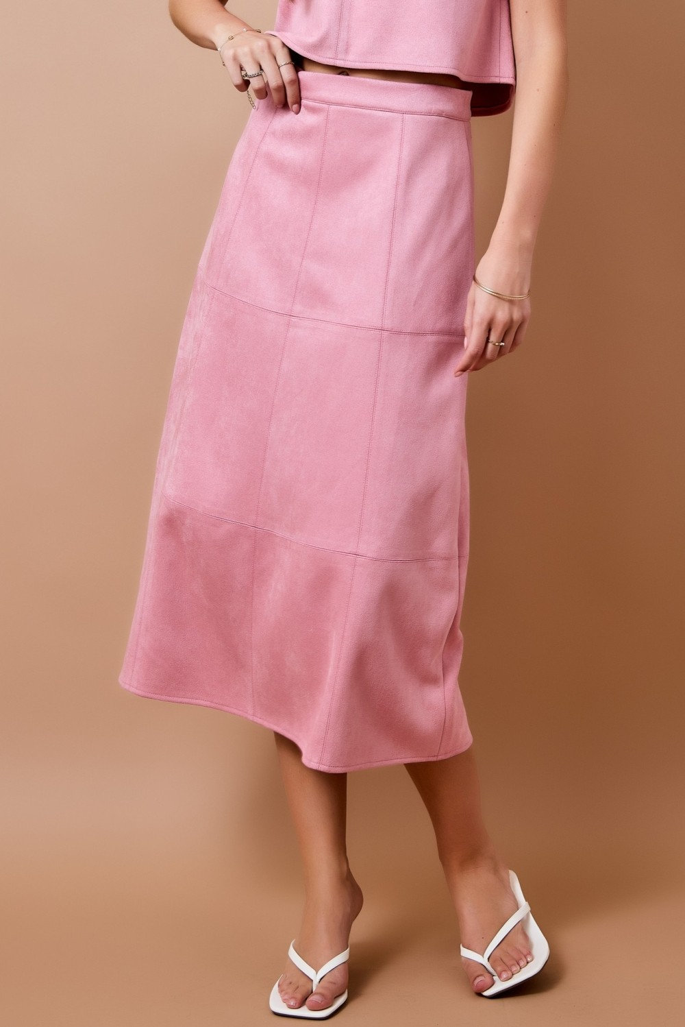 Pink high-waisted suede A-line midi skirt with panel seam detailing.