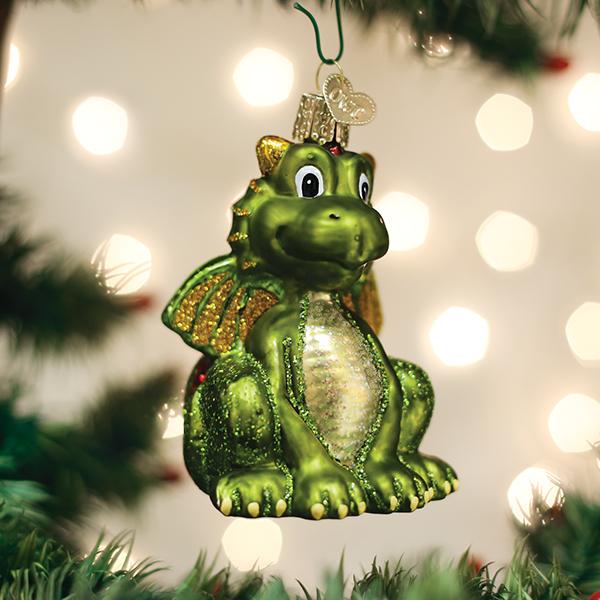 Green glass Little Dragon ornament with gold glitter wings hanging on a Christmas tree.