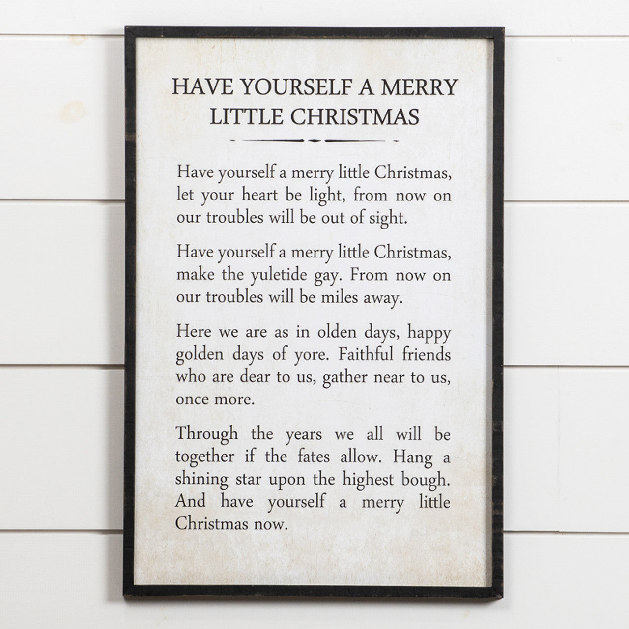 Wooden Merry Little Christmas sign with white lettering on a natural wood background.