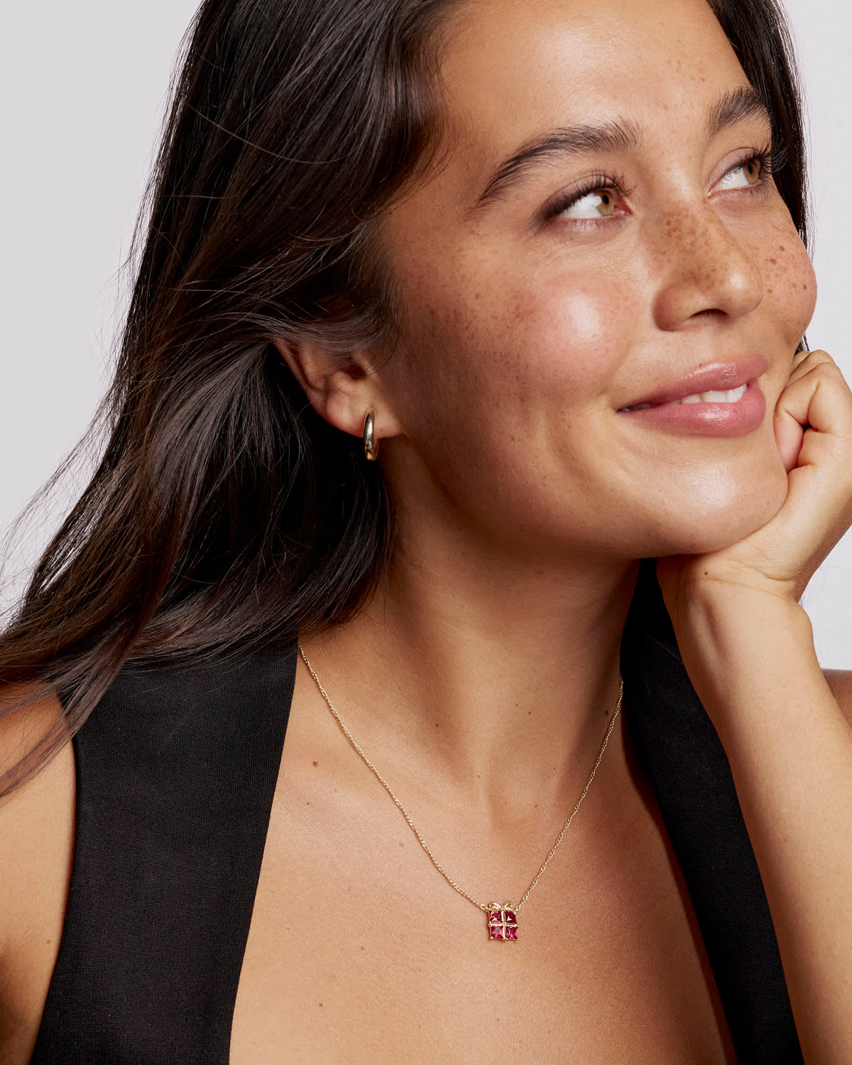 A woman wearing the Present Short Pendant Necklace in gold with a red crystal gift box pendant.