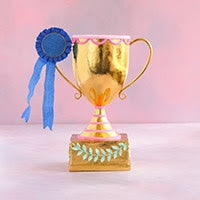 A 21.5-inch gold trophy with pink accents and a blue ribbon against a pink background.