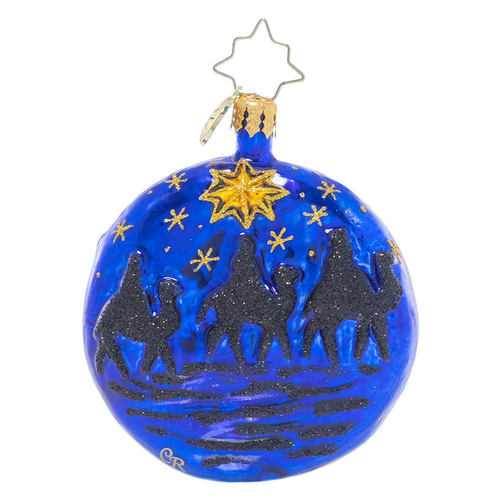 Blue glass ornament featuring three wise men on camels under a gold star and night sky.