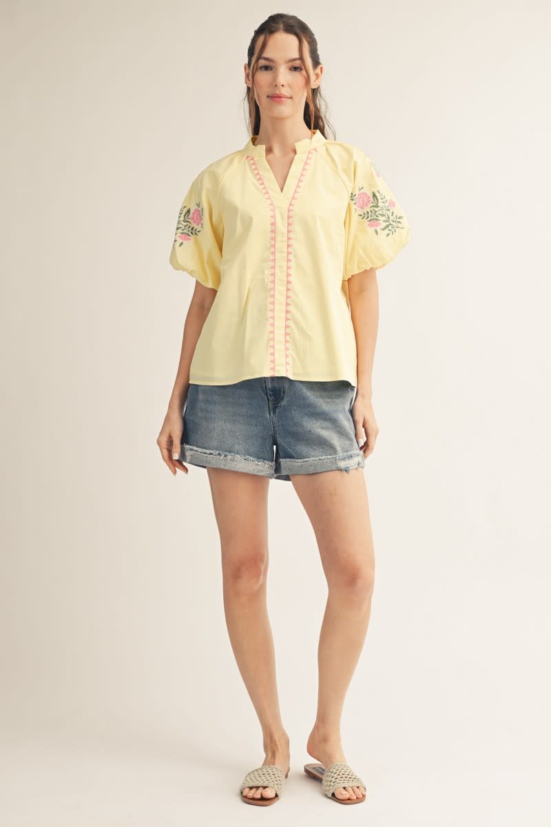 Boho cotton blouse with split V-neckline, geometric embroidery, voluminous puff sleeves, and floral details.