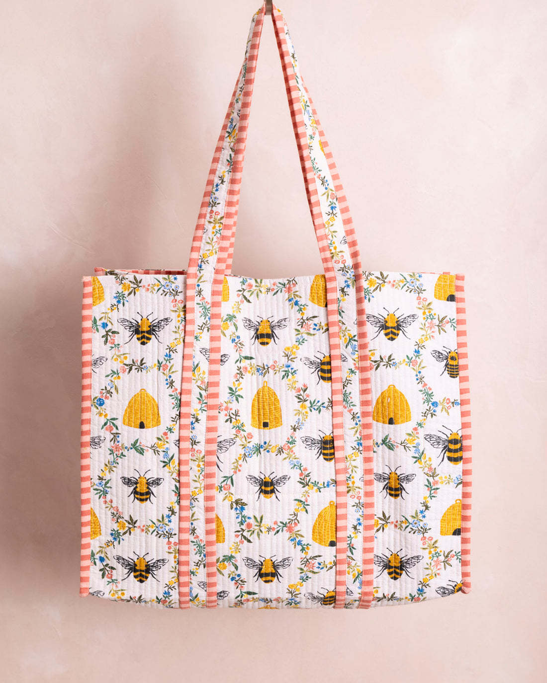 The Traveler Tote in Sweet Bee, a white quilted organic cotton bag with bee and floral patterns.
