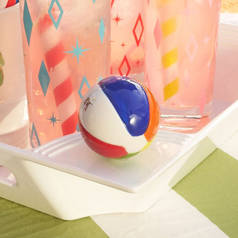 Hand-painted beach ball mini ornament on a white serving tray with pink summer drinks.
