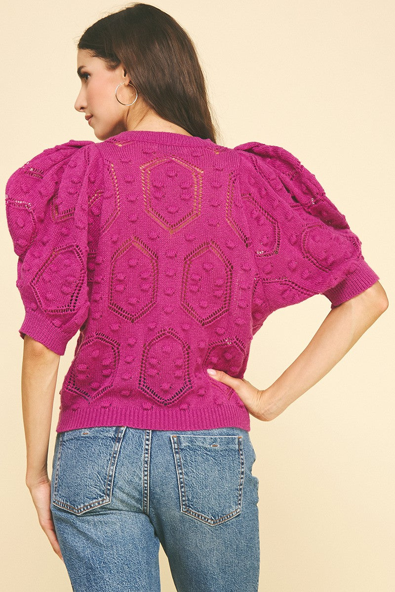 Back view of a woman wearing a magenta Alexia puffed sleeve embroidered sweater with blue jeans.