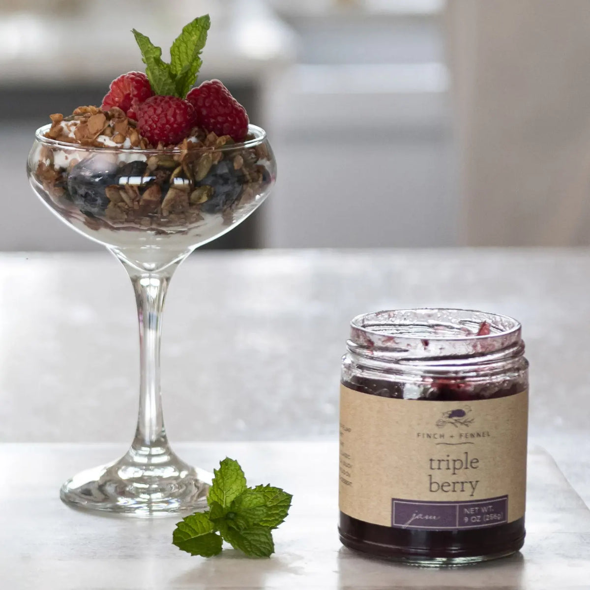 Glass jar containing Triple Berry Jam with visible red strawberries, blueberries, and raspberries.