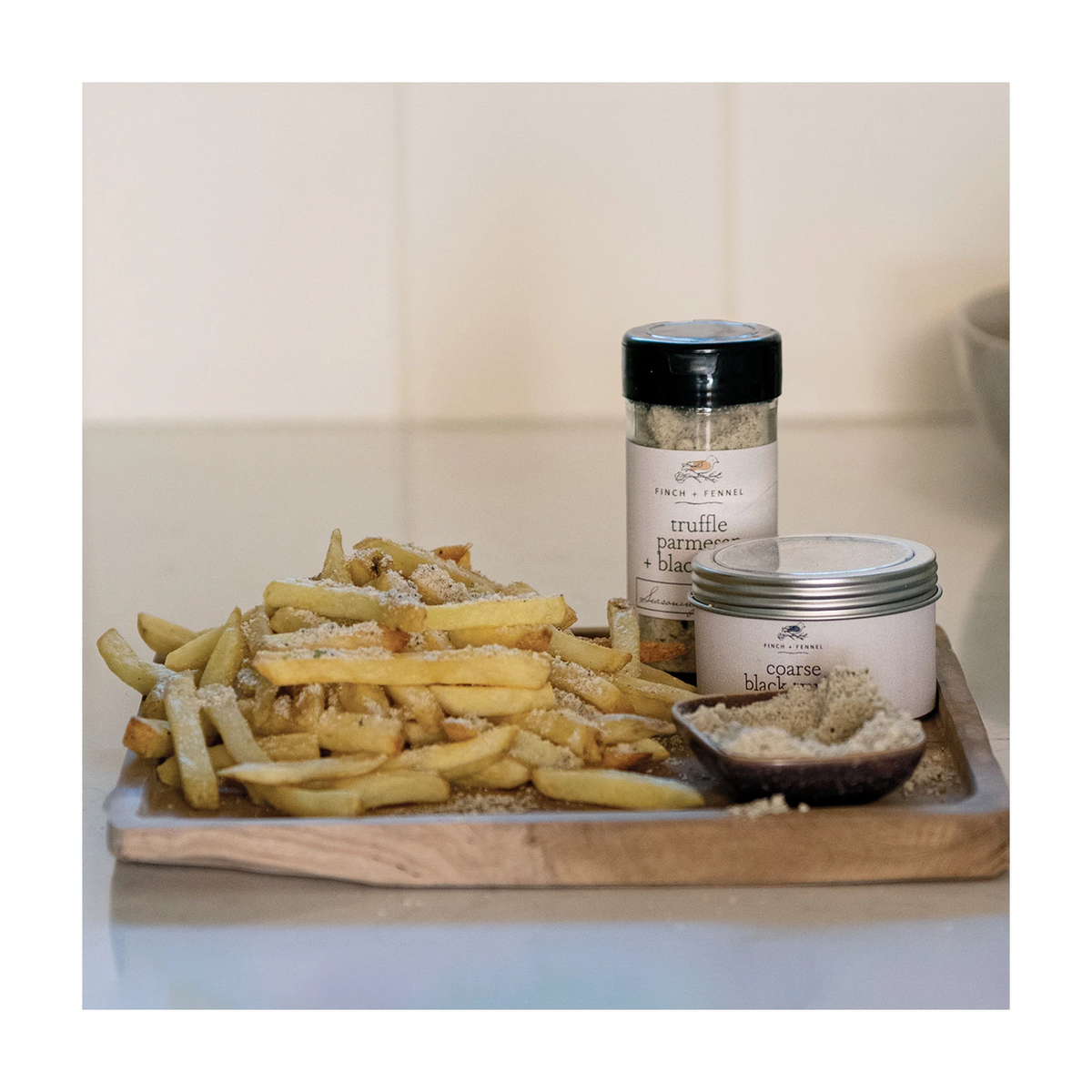 Truffle Parmesan + Black Garlic seasoning blend in a round container with visible speckled herbs.