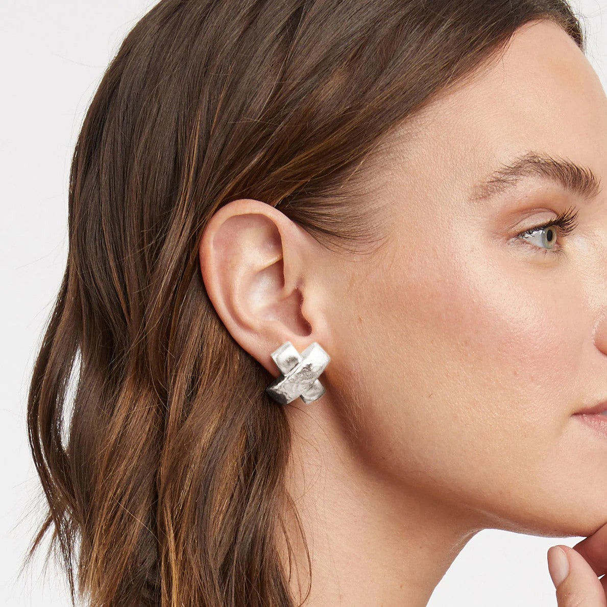 Woman wearing a silver Catalina X earring with hammered and smooth textured bars.
