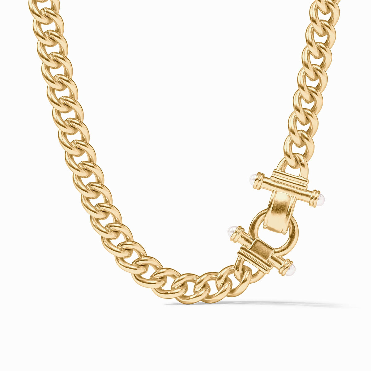 Gold curb link necklace with a decorative fold-over clasp accented with small white glass pearls.