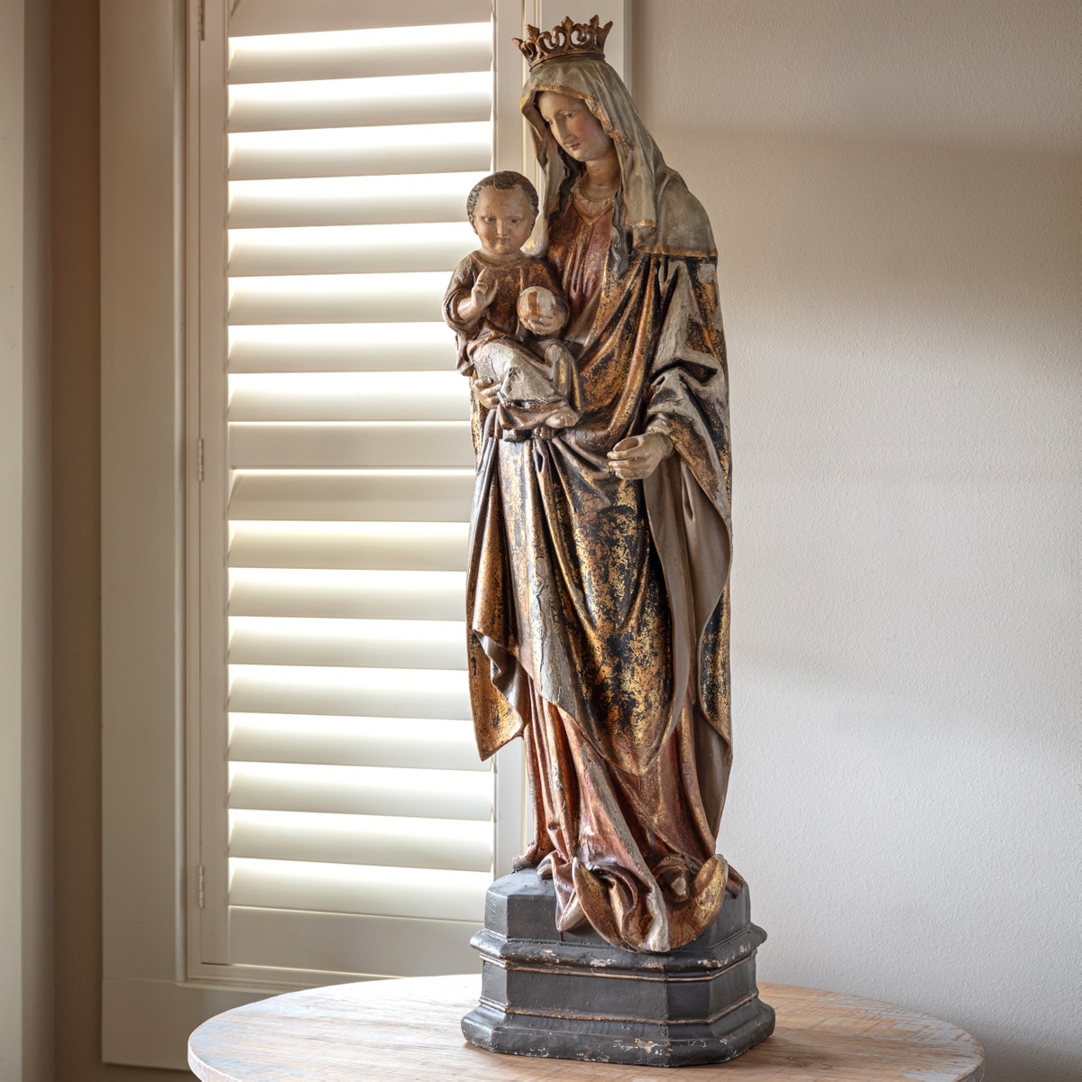 Large gilded plaster statue of the Madonna and Child standing on a dark pedestal.