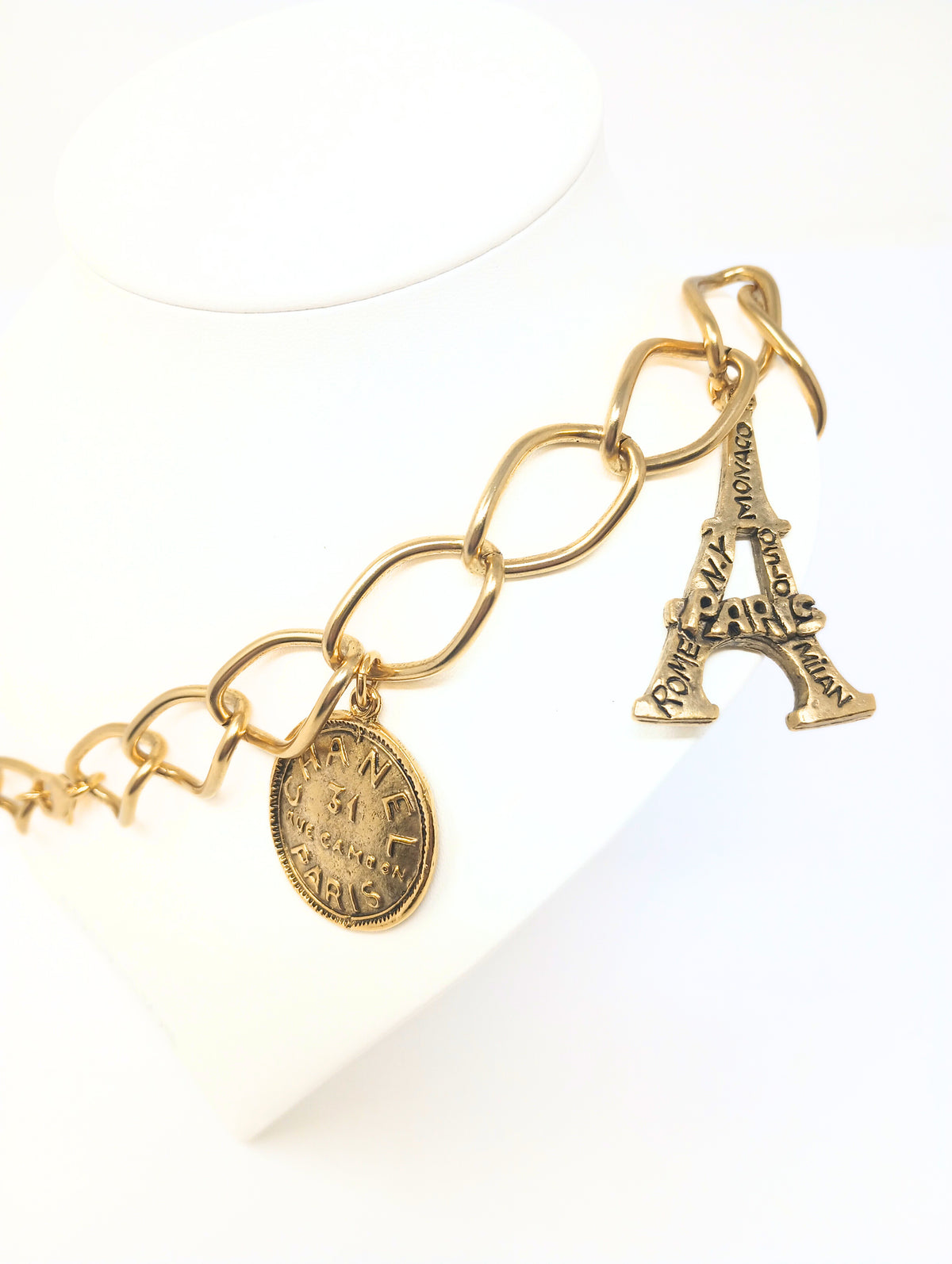 Gold link necklace featuring five charms: Paris heart, Eiffel Tower, number five, and two Chanel-style coins.