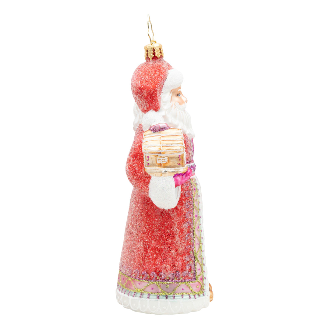 Side view of a red glittered Santa ornament holding a gingerbread house.