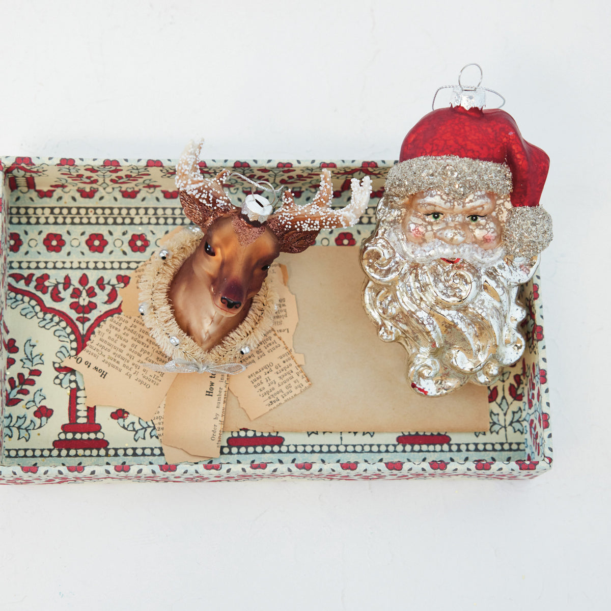 Hand-painted mercury glass Santa head ornament with mica flakes and a red hat in a patterned box.