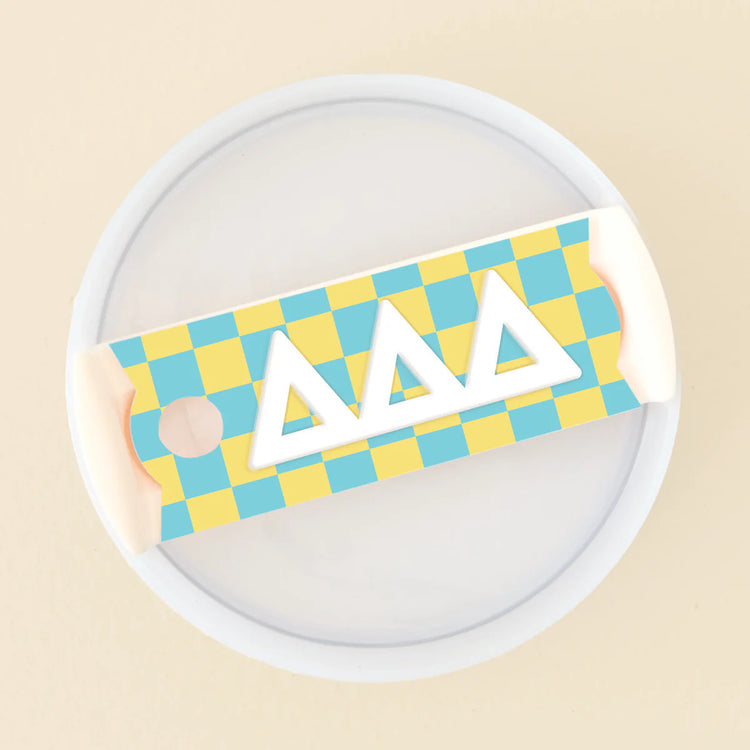 Acrylic tumbler lid tag with a yellow and blue checkered pattern and white Delta Delta Delta letters