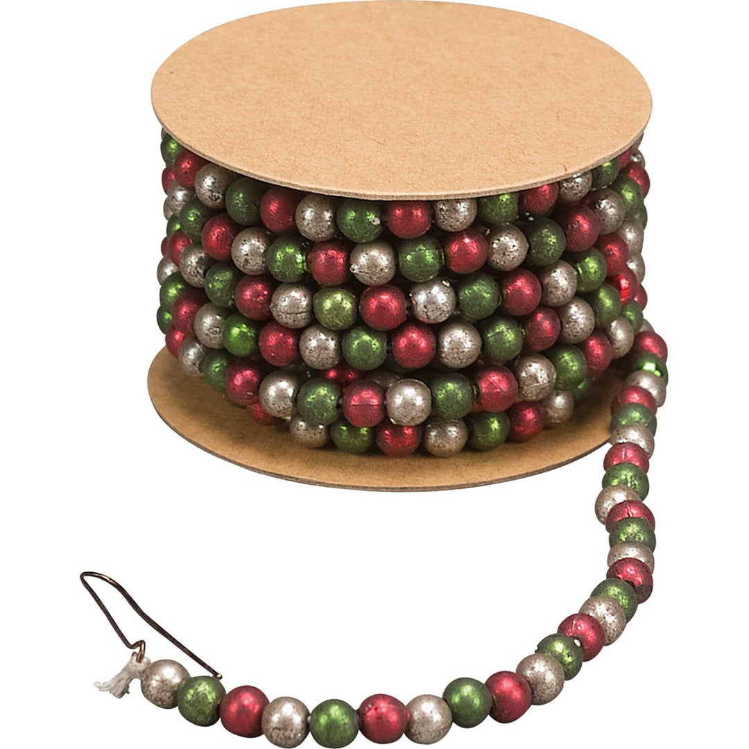 Red, green, and silver bead garland wrapped around a cardboard spool with a metal hook.
