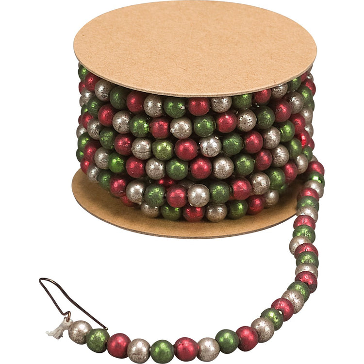 Red, green, and silver bead garland wrapped around a cardboard spool with a metal hook.