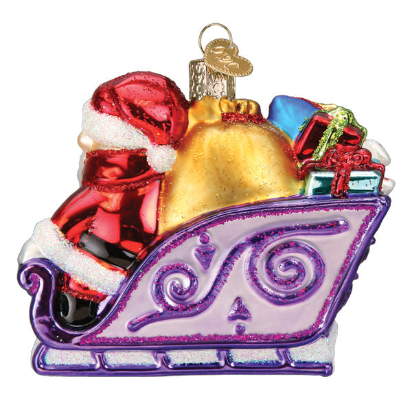 Glass Santa ornament in a purple glittery sleigh filled with a gold sack and colorful presents.