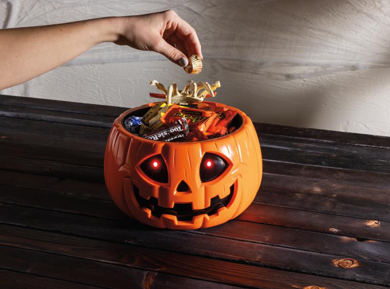 Animated orange Jack-O-Lantern candy bowl with glowing red LED eyes and a skeleton hand.