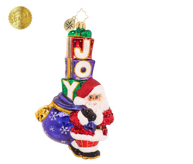 Santa Claus ornament carrying a blue sack and a stack of gift boxes spelling JOY.