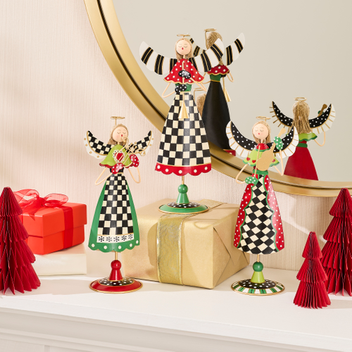 Three decorative tin angels with checkered patterns and wings on a mantel with holiday gifts.