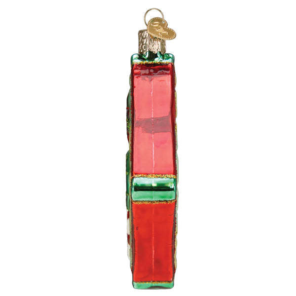 Glass Christmas quilt ornament featuring a patchwork fabric design with red, green, and cream squares.