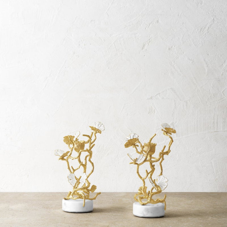 Set of two gold butterfly ginkgo candleholders with white enamel leaves on marble bases.
