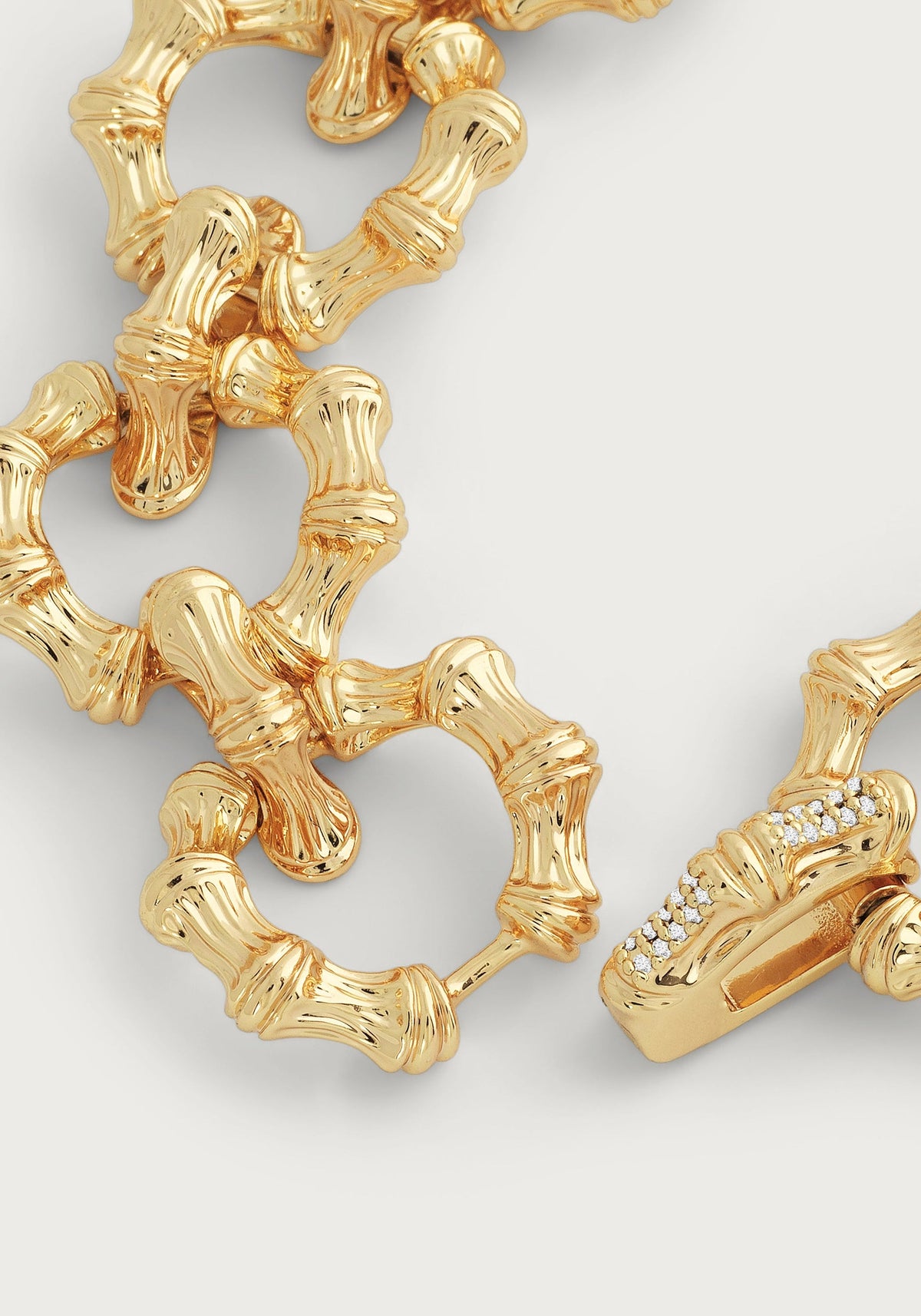 Close-up of an 18K gold-plated bamboo chain bracelet with a crystal pavé hidden closure.