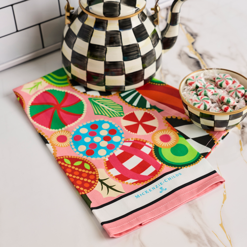 Jolly Ornaments Printed Dish Towel with colorful holiday patterns next to a checkered teapot.