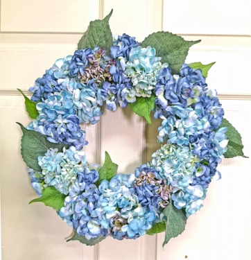 Round hydrangea wreath with pink flowers on a natural green base.