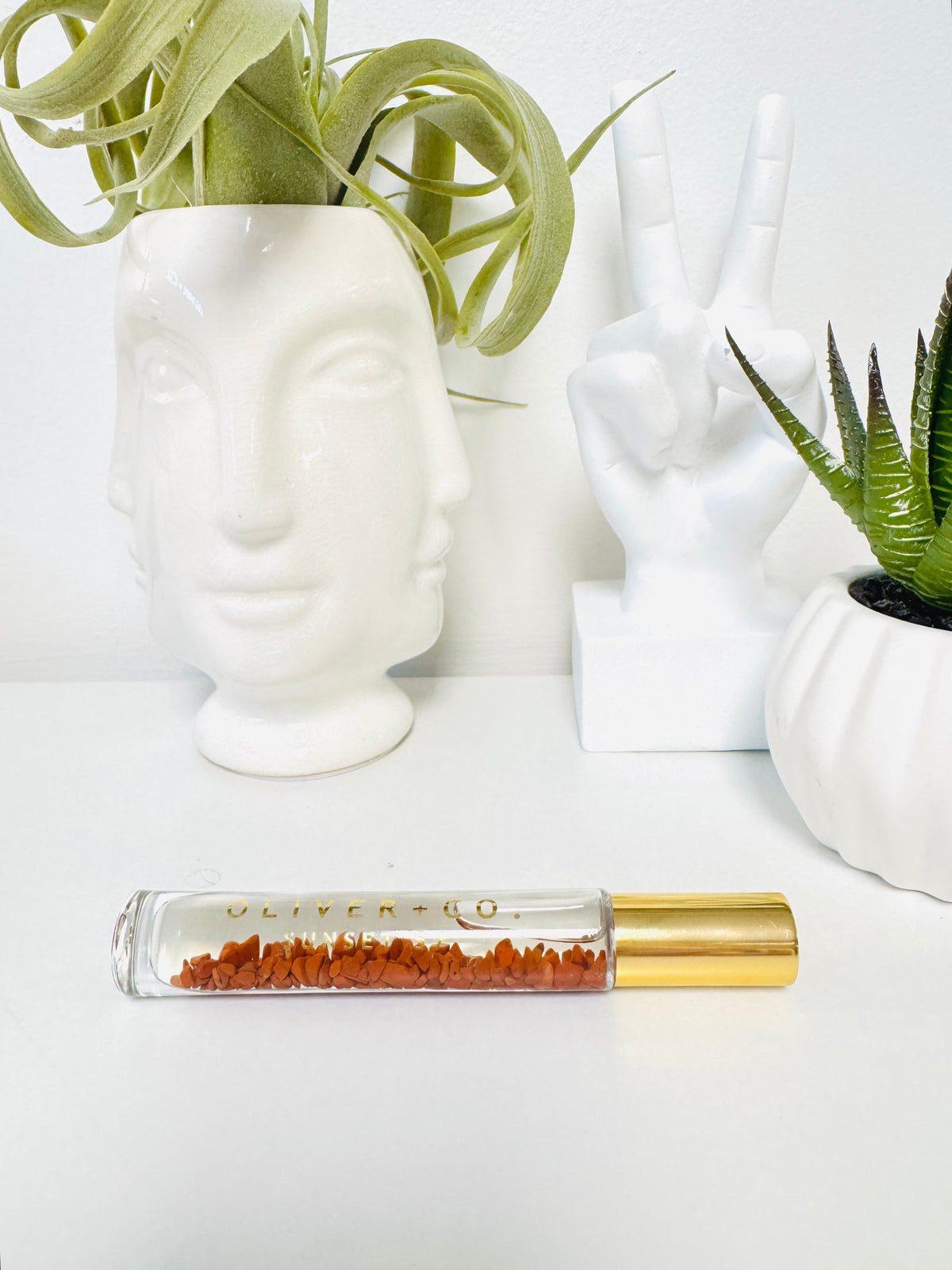 Bougie Stick roll-on perfume bottle with gold cap and red crystals inside, on a white surface.