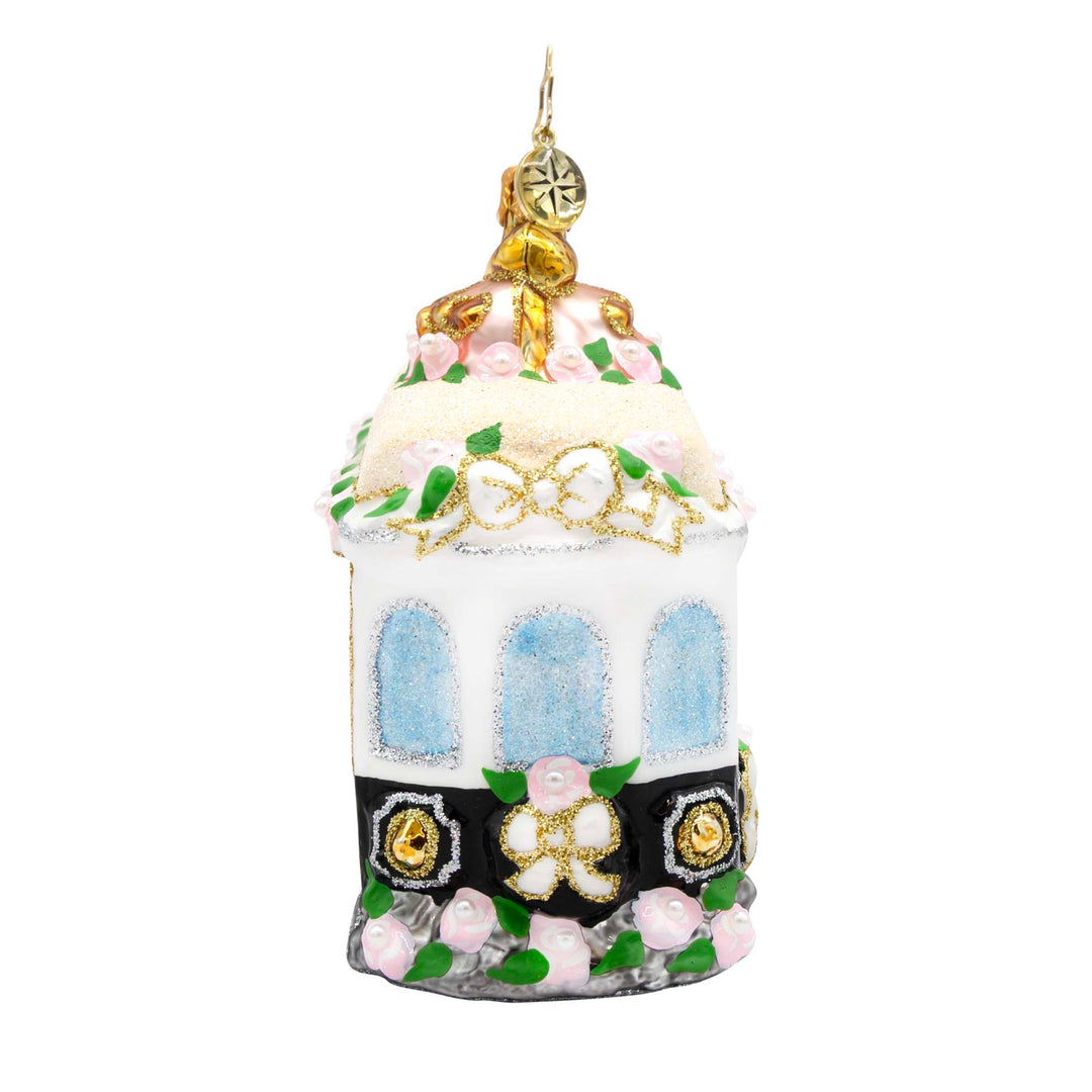 White and black glass trolley ornament with pink roses, glittery windows, and gold accents.