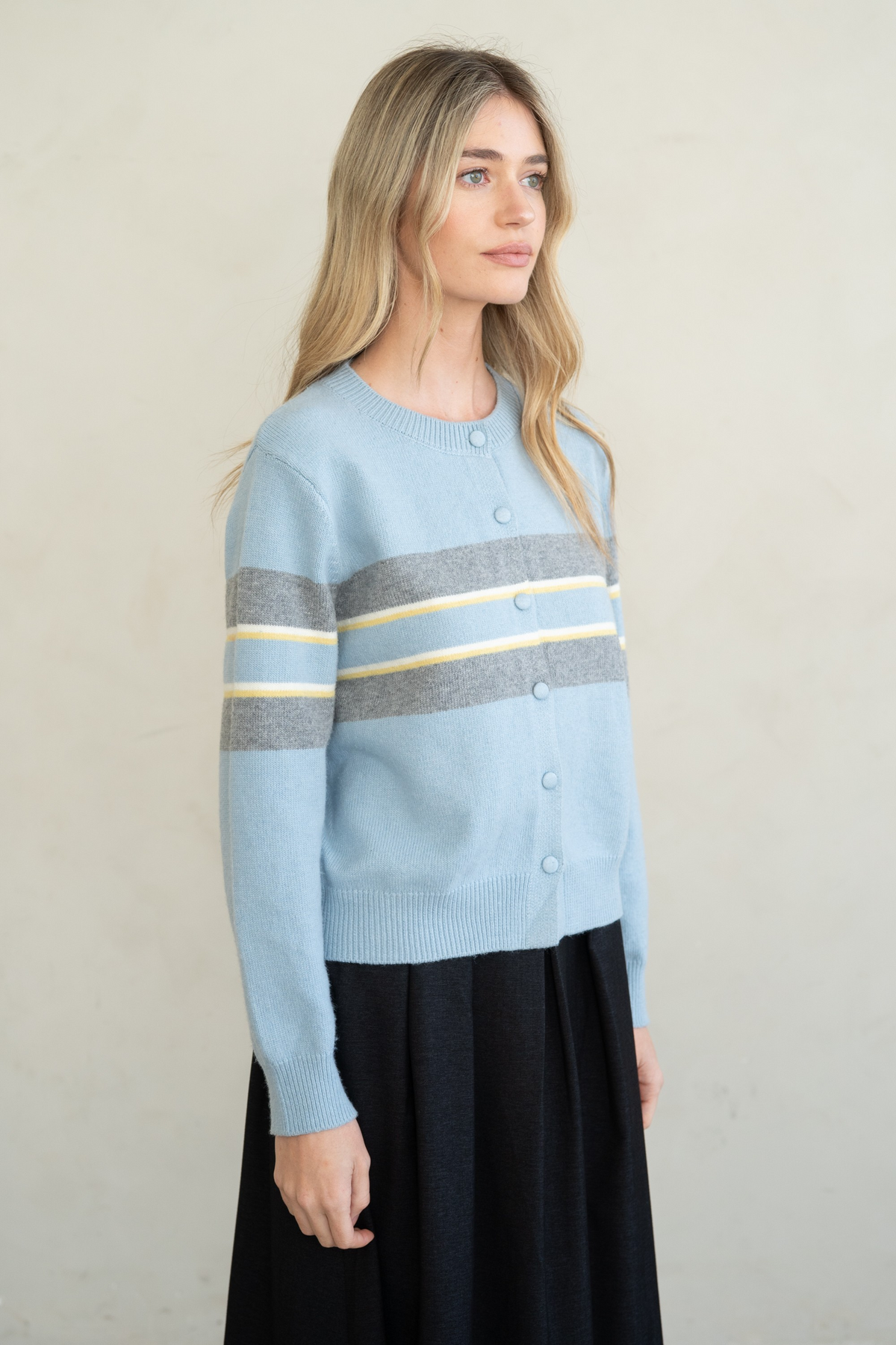 Woman wearing a light blue Natalie Soft Touch Crew Neck Cardigan with grey and yellow stripes.